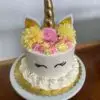 Unicorn themed birthday cake with rosettes and artificial flowers