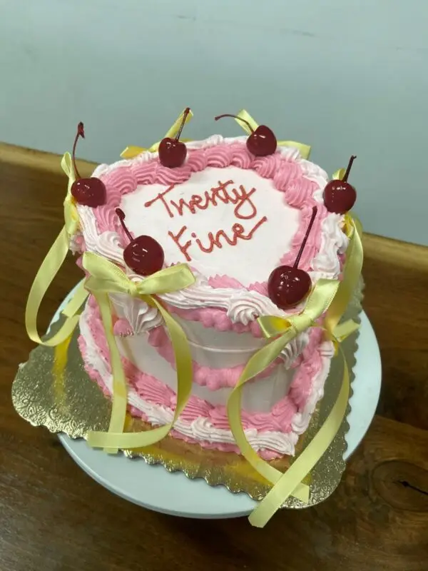Lambeth heart 2-color with light pink and pink icing, cherries, and light yellow ribbon